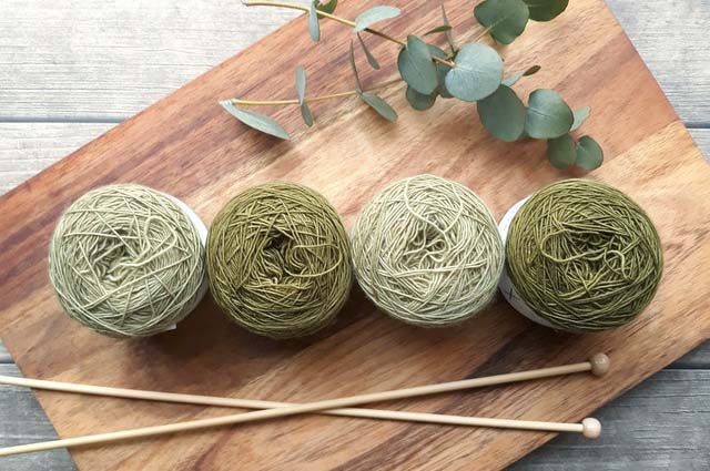 Four green yarns balls on a chopping board