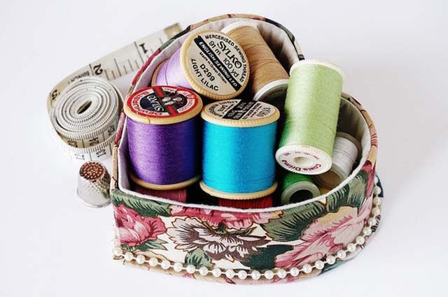 a heart shaped basket with multicolored thread inside